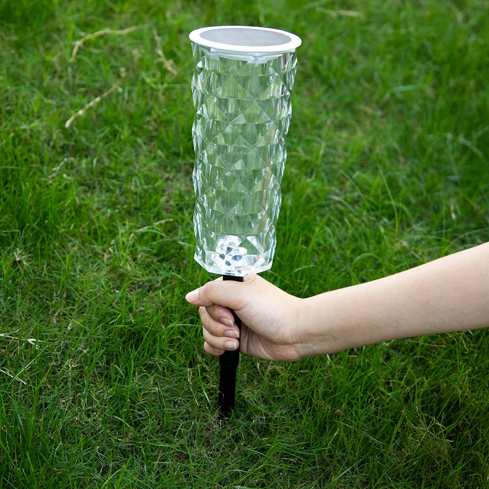 Havenlia solar rose garden stake light glowing in flower bed at dusk